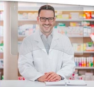 A pharmacist stands behind a hanging barrier.