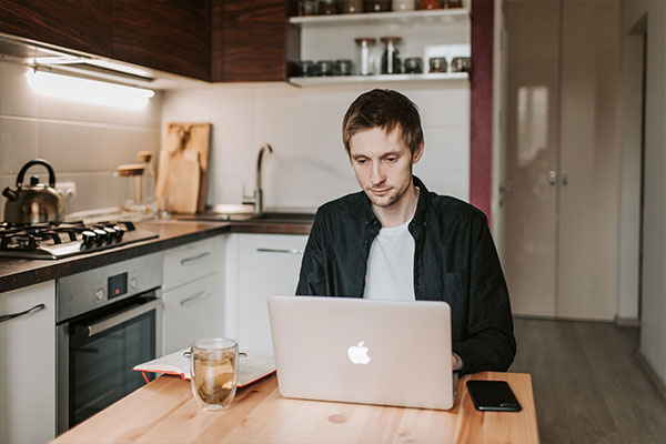 man on macbook at butchers block table