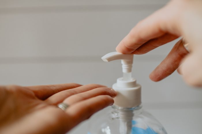 Using a sanitizer dispenser on the hands