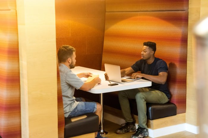 Two workers sitting down, collaborating on an assignment